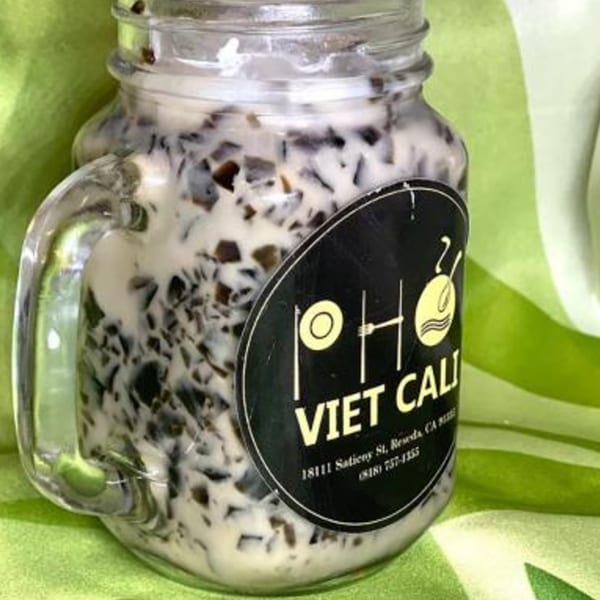 A glass jar of Vietnamese grass jelly dessert with coconut milk, branded "Pho Viet Cali".