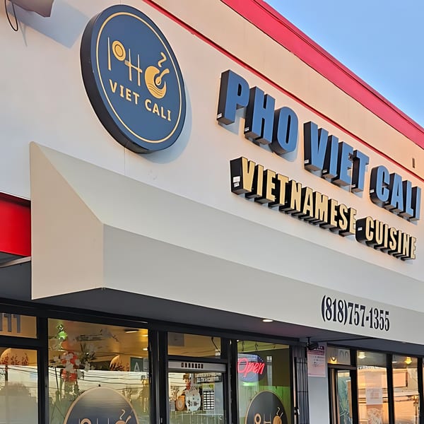 Exterior of Pho Viet Cali restaurant with its circular logo and large "PHO VIET CALI VIETNAMESE CUISINE" sign.