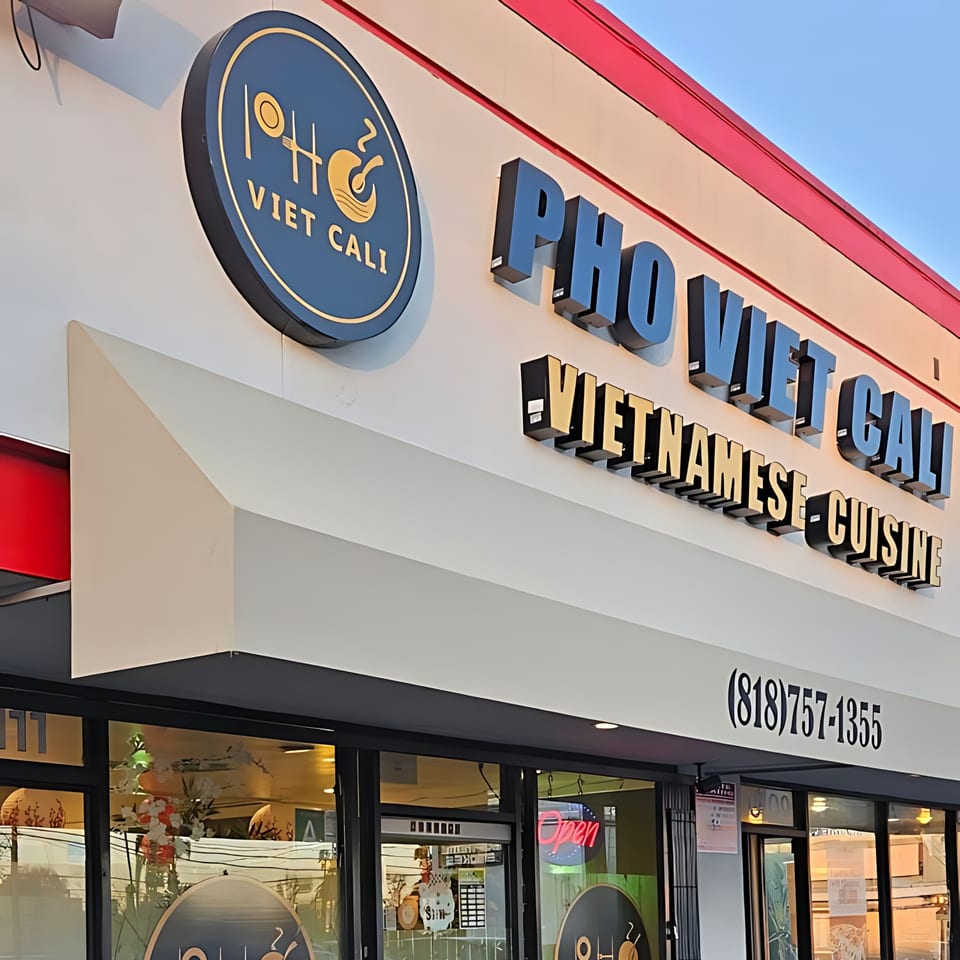 Exterior of Pho Viet Cali restaurant with its circular logo and large "PHO VIET CALI VIETNAMESE CUISINE" sign.