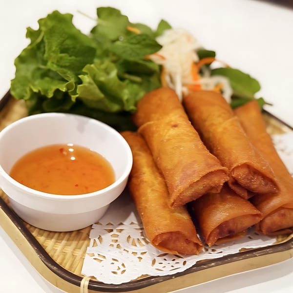 Crispy Vietnamese egg rolls with a side of sweet chili sauce and fresh lettuce.