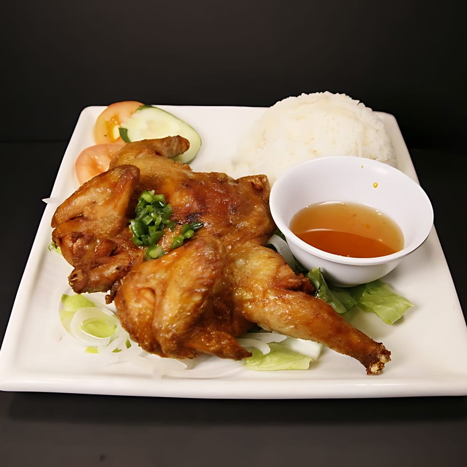 Whole roasted chicken with rice, sliced tomatoes, cucumbers, and a side of dipping sauce.
