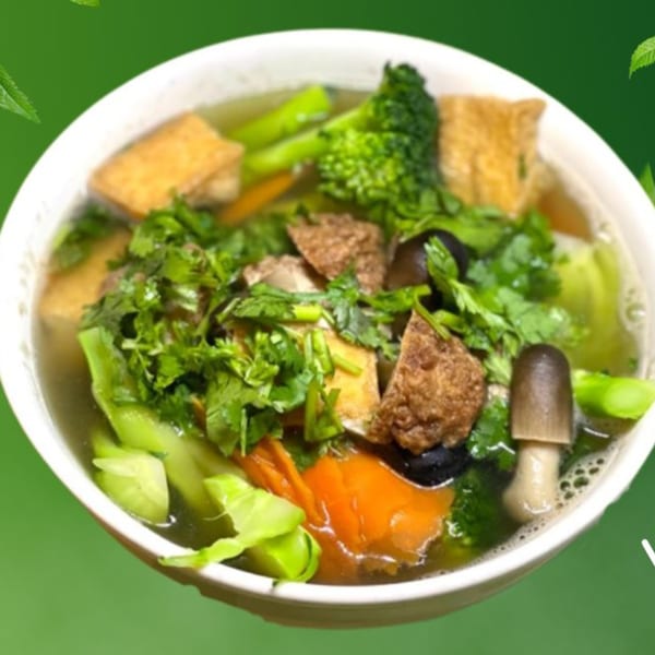 A bowl of Pho Viet Cali's Vietnamese soup with tofu, broccoli, carrots, and mushrooms.