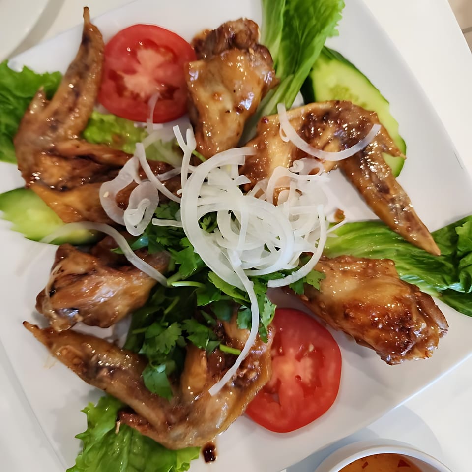 Vietnamese glazed chicken wings with sliced tomatoes, cucumbers, lettuce, cilantro, and onions.