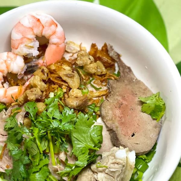 A close-up of a Vietnamese dish with shrimp, meat, fried onions, and fresh cilantro.