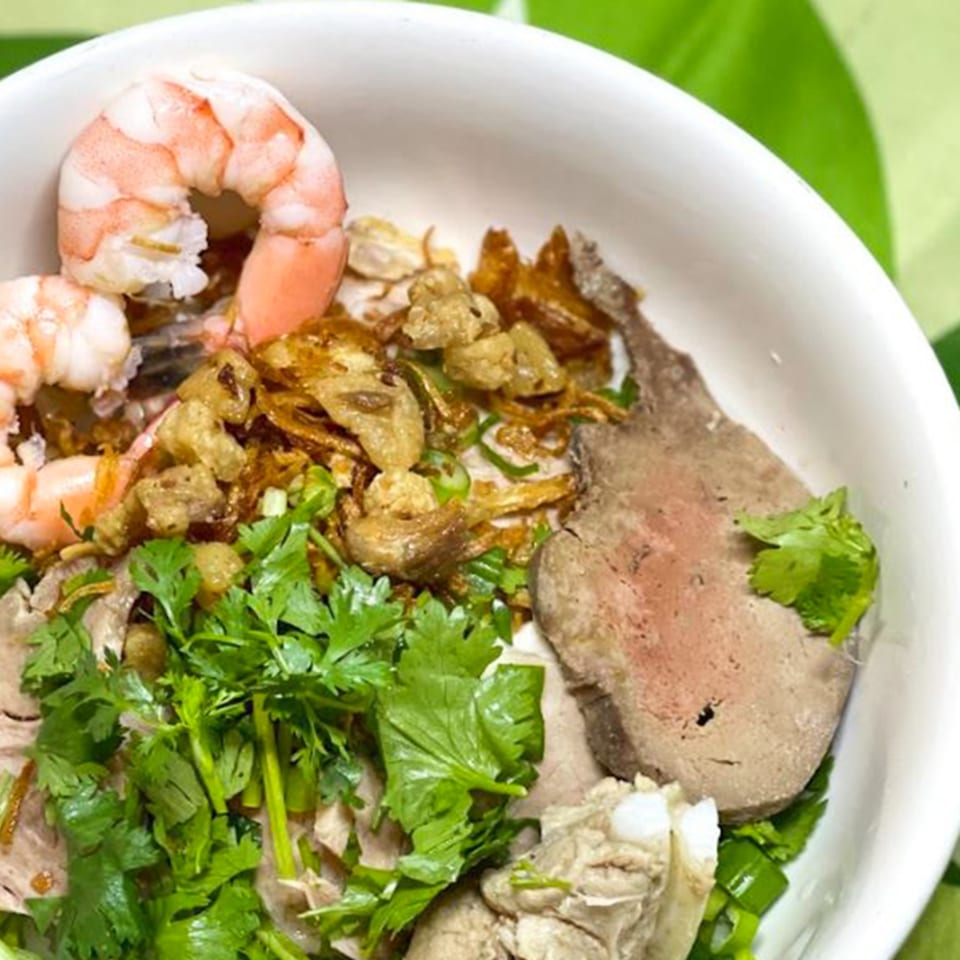 A close-up of a Vietnamese dish with shrimp, meat, fried onions, and fresh cilantro.