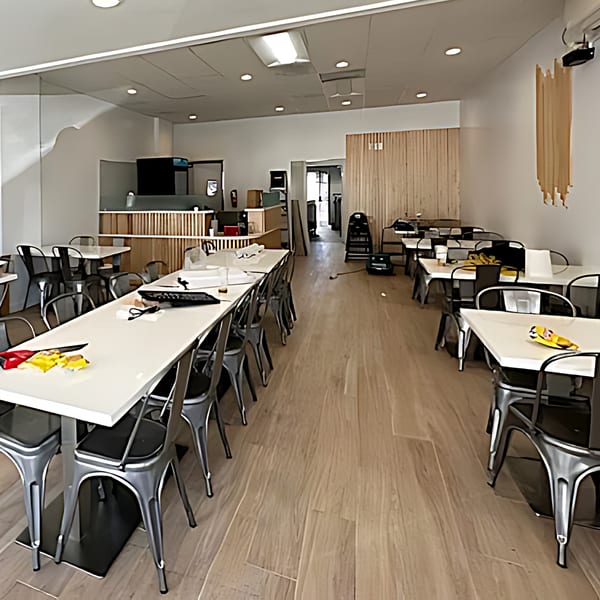 Interior of Pho Viet Cali, showing an empty dining room with long tables and metal chairs.