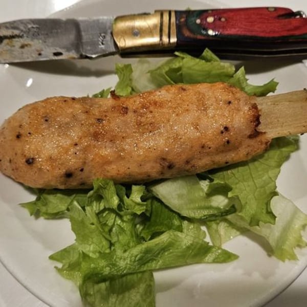 Grilled Vietnamese shrimp paste on sugarcane, served with fresh lettuce and a knife.